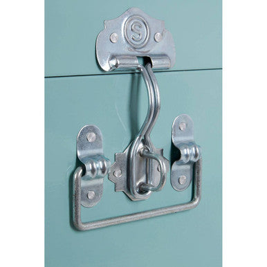 Silver-toned metal latch and handle set with vintage design on two green storage trunks mint green cabinet