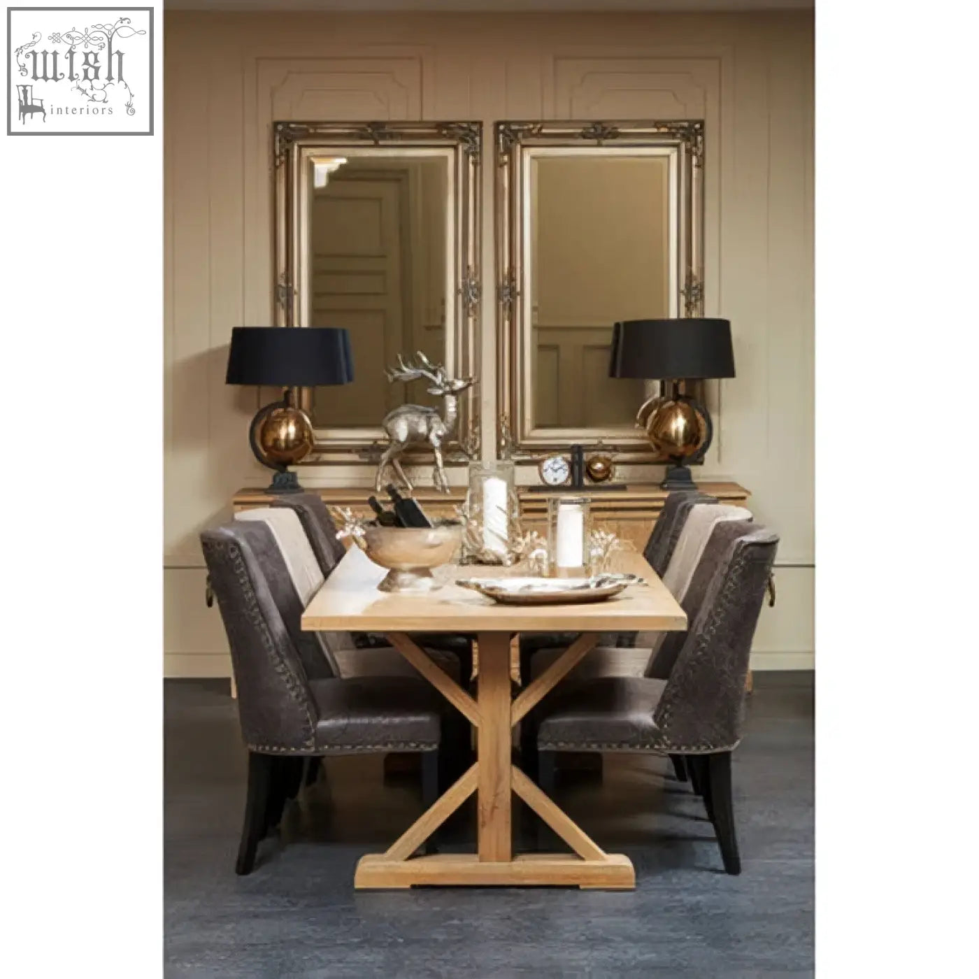 Light oak wooden dining table with cross-shaped base and dark gray chairs shown with sevan wood frame wall mirror