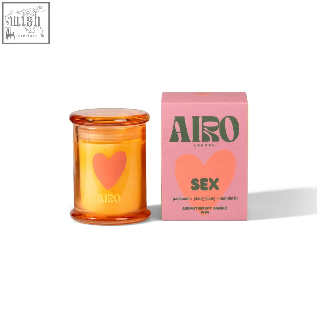 A vibrant orange glass sex mini candle with a heart design and essential oils by airo next to pink packaging