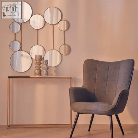 Gray tufted armchair with black metal legs next to a medium speckled vase perfect for stylish home decor