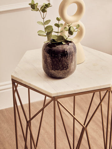 Dark textured ceramic vase with eucalyptus leaves on shalimar marble top side table with geometric base and marble surface
