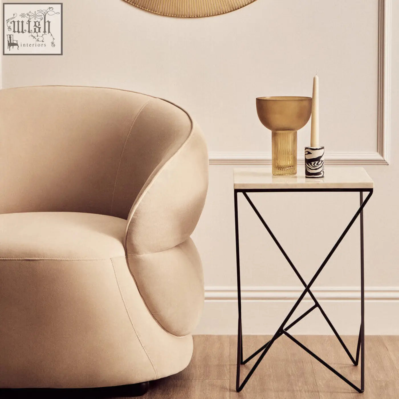 Cream-colored velvet armchair next to shalimar marble top square side table with black iron base