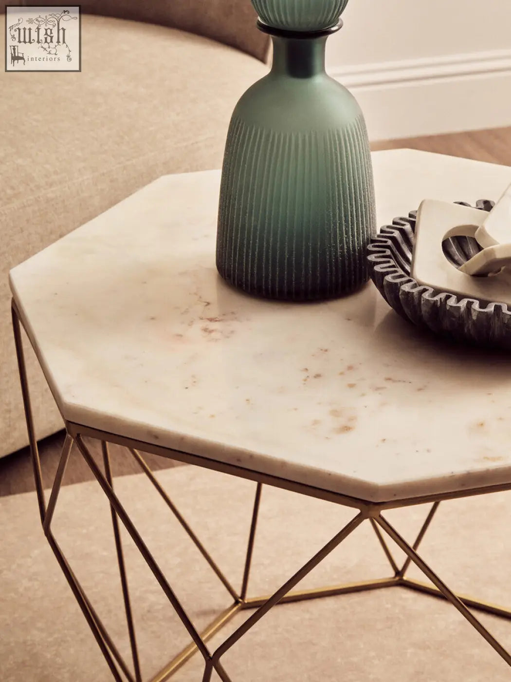 A sleek green glass decanter on a dark octagon white marble coffee table with a white marble top