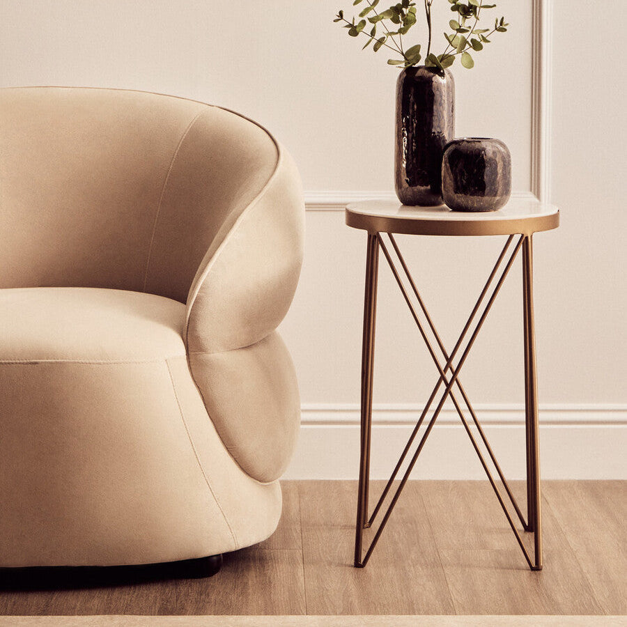 Beige velvet armchair with rounded contours and plush seat paired with shalimar round marble top side table for living room