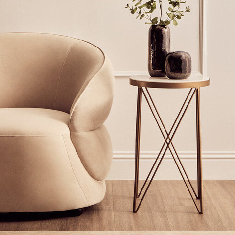 Beige velvet armchair with rounded contours and plush seat paired with shalimar round marble top side table for living room