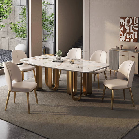 Modern marble-top dining table with sleek gold-toned curved pedestal legs paired with shankar leather dining chair