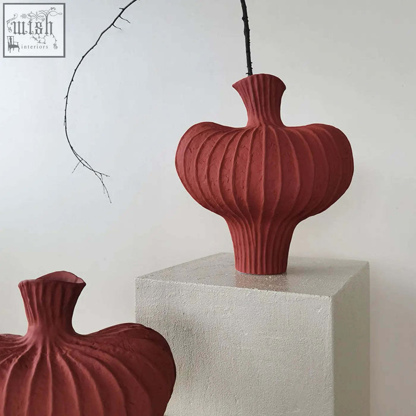 A red shaped ceramic vase with a bulbous heart-shaped body and vertical ridges made of terracotta