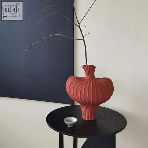 A terracotta-colored shaped ceramic vase with a ribbed organic design and a flared neck perfect for decor