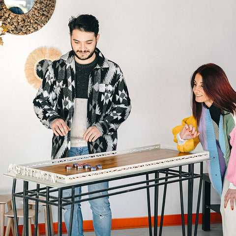 A sleek modern shuffleboard game board with wooden top and white metal frame suitable for all age range and easy hanging instructions