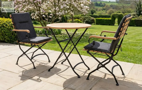 Black cushioned folding patio chairs with wooden armrests and slatted back in a sicily 2 seater garden dining set with grade ab teak