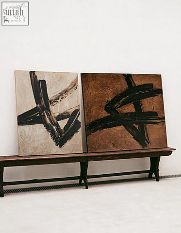 Two siegmund wall art paintings with bold black brushstrokes on beige textured canvases on a dark wooden bench ideal for wall art painting shipping cost info available