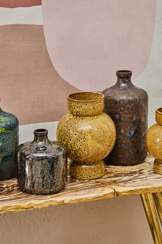 Golden ceramic vase with textured perforated surface and rounded body in silas dark blue bottle design