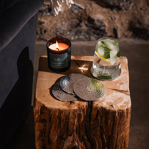 Set of four silver flat hammered coasters made of metal with a textured dimpled surface for drinks