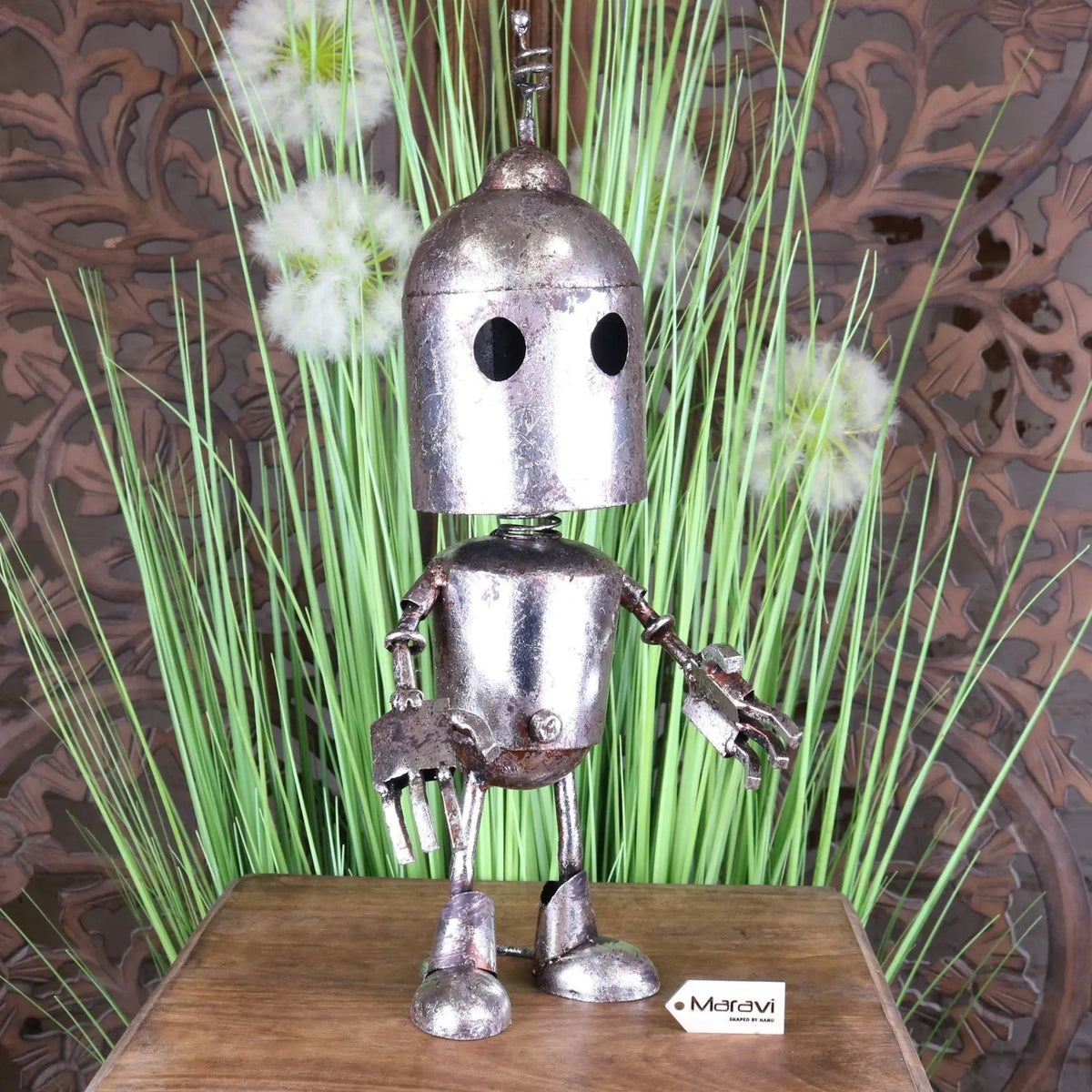 A rustic silver robot ornament with a rounded head black eyes and articulated limbs for springy bobble head fun