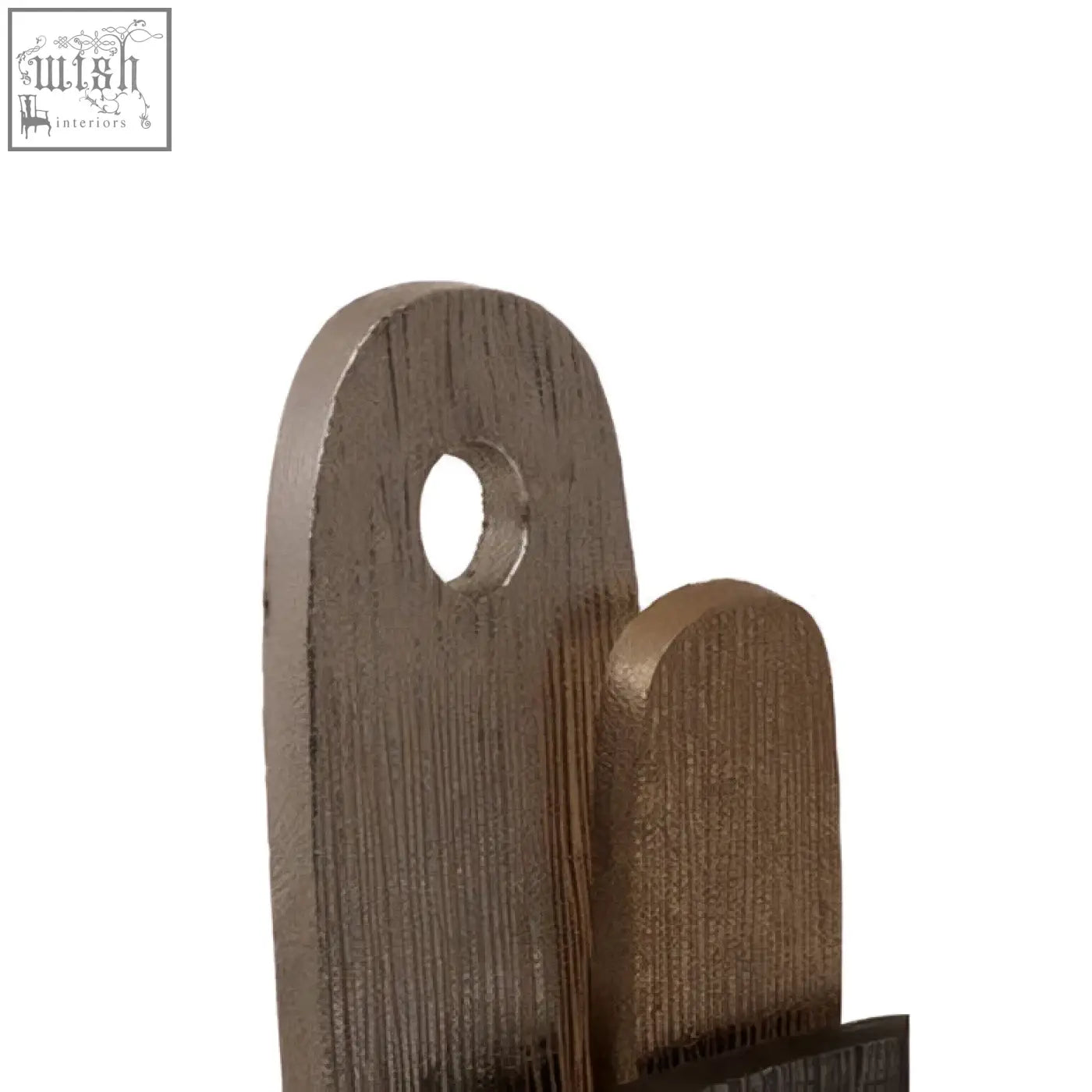 Dark brown wooden cutting board with rounded top and hole next to simbolo small assorted metal sculpture on marble base