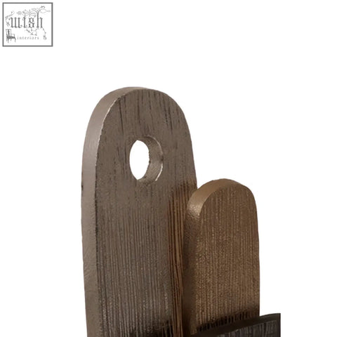 Dark brown wooden cutting board with rounded top and hole next to simbolo small assorted metal sculpture on marble base