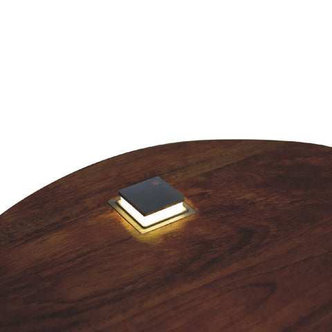 Single chestnut bedside table with a square modern led lamp featuring a sleek black top and warm white light base
