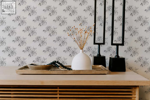 White ceramic vase with vertical ridges holding dried stems on black and white sketch rose peel and stick wallpaper perfect for living space ordering process