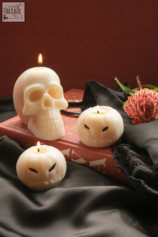 Cream-colored skull candle made of wax with a lit wick perfect for spooky decor and ambiance