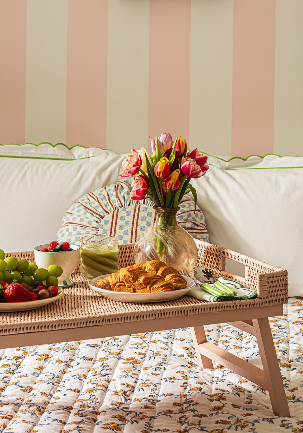 Woven rattan tray with sky blue scalloped nibbles bowl set holding colorful tulips and assorted pastries grapes berries