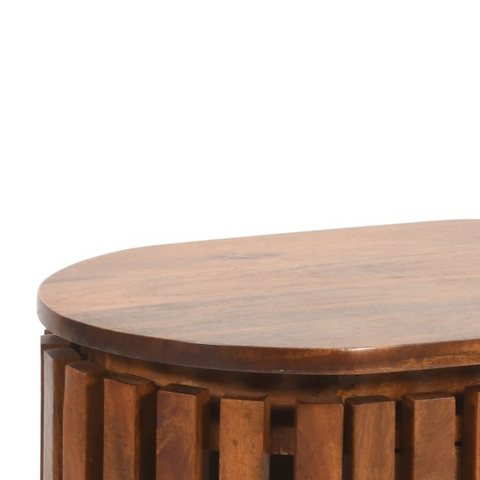 Warm brown slatted mango wood bedside table with smooth oval top and vertical slat detailing on cylindrical base