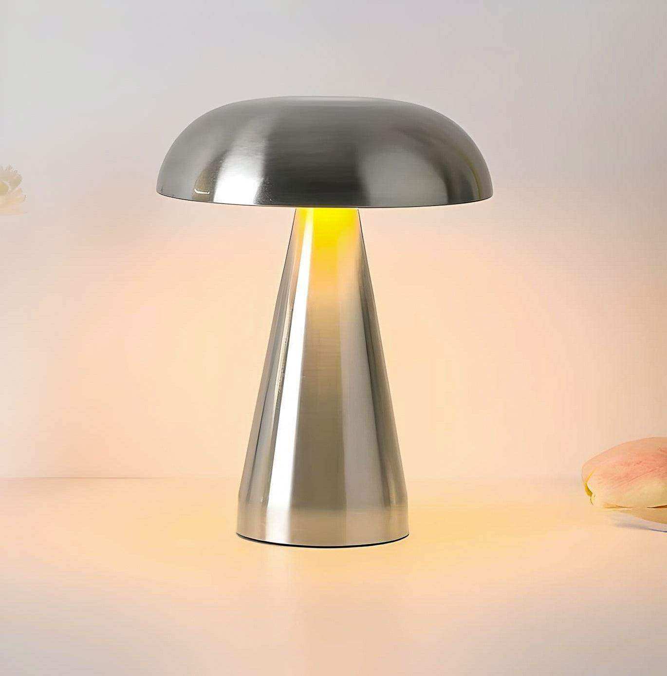 A sleek abstract lamp with a mushroom shape, brushed metallic finish, and warm yellow light from its base