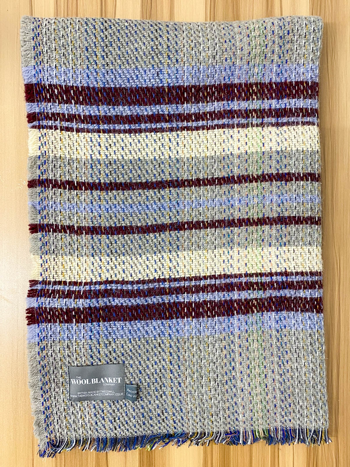 A cozy small checked random recycled wool blanket with blue maroon cream stripes and fringed edges