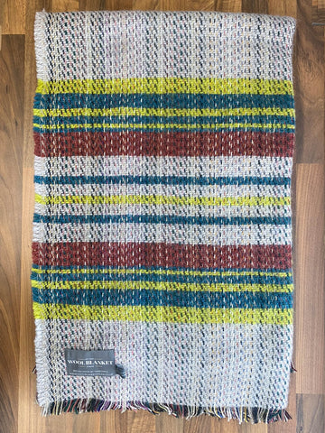A cozy small checked random recycled wool blanket with bold yellow teal and rust stripes and fringed edges