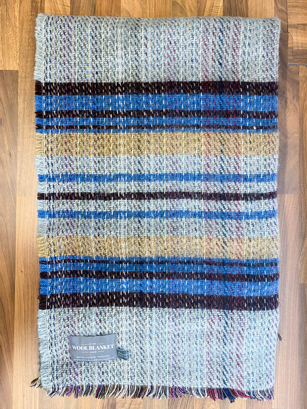 A cozy small checked random recycled wool blanket with blue beige and burgundy stripes and fringed edges