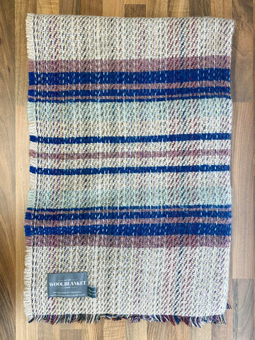 A cozy small checked random recycled wool blanket with blue beige and muted red stripes and fringed edges