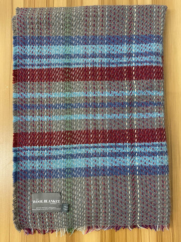 A cozy small checked random recycled wool blanket with a rich gray blue red and green plaid and frayed edges