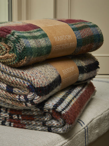 Stacked small checked random recycled wool blankets with handwoven plaid in earthy red green beige and navy tones