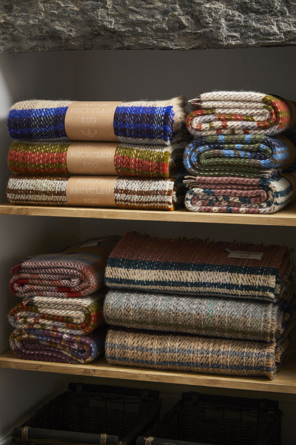 Stacks of small checked random recycled wool blankets with earth tones and textured multicolored natural fibers