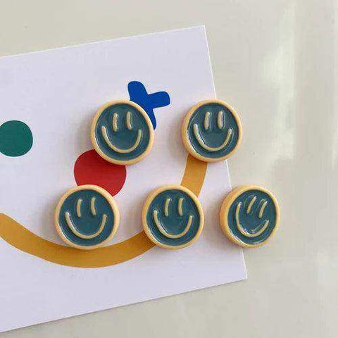 Five teal smiley face glow fridge magnets with light wood border in a smiling glow fridge magnet pack