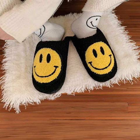 Black fuzzy smiling slippers with bright yellow smiley face design made of soft faux fur for cozy wear