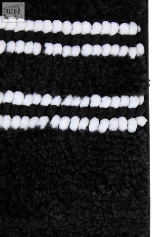 Large charcoal grey plush bath mat with soft white pom-pom trim for cozy bathroom use