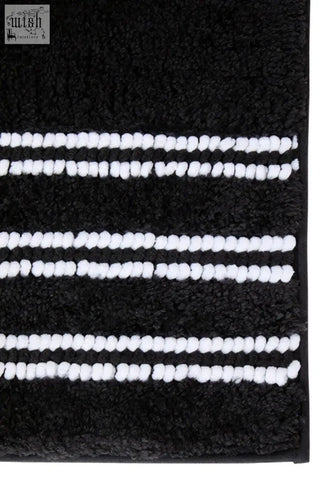 Large charcoal grey bath mat with plush black fabric and three white textured yarn stripes for cozy bathroom use