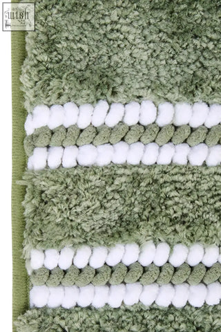 Olive green plush bath mat with textured surface and white pom-pom stripes perfect for a sage green bath