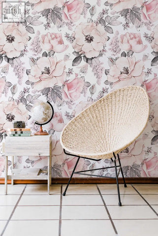 Beige woven wicker chair with black metal legs against soft pink abstract roses peel and stick wallpaper in living space
