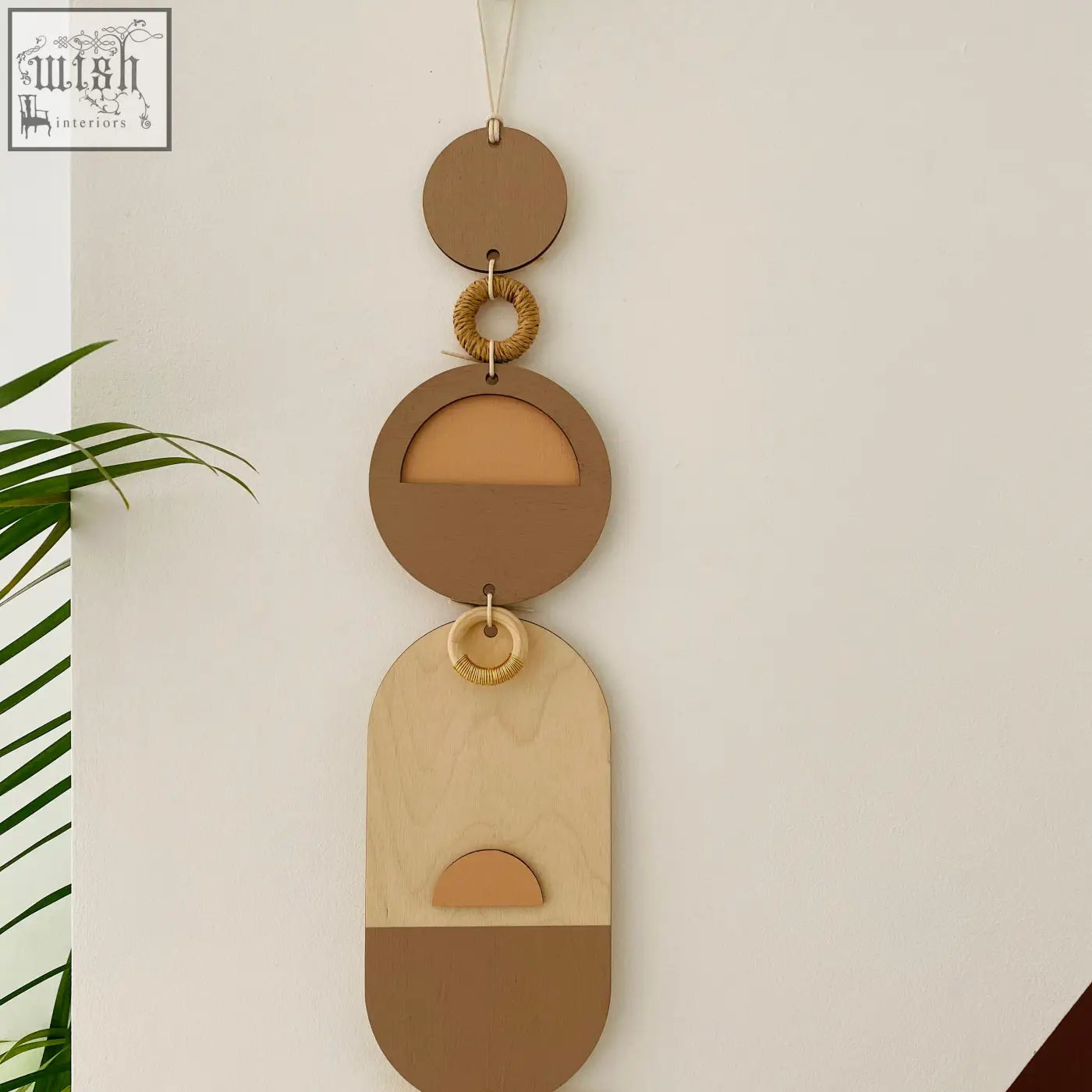Soft pink modern wall art with terra-toned layered wooden circles and woven rattan rings for neutral home decor