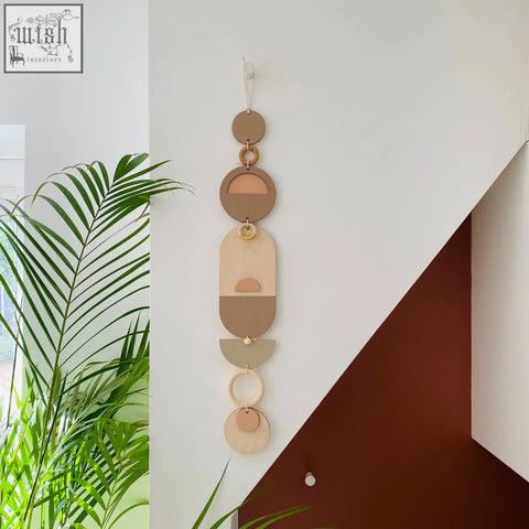 A modern wall art with stacked circular shapes in earthy tones featuring natural wood and subtle metallic accents