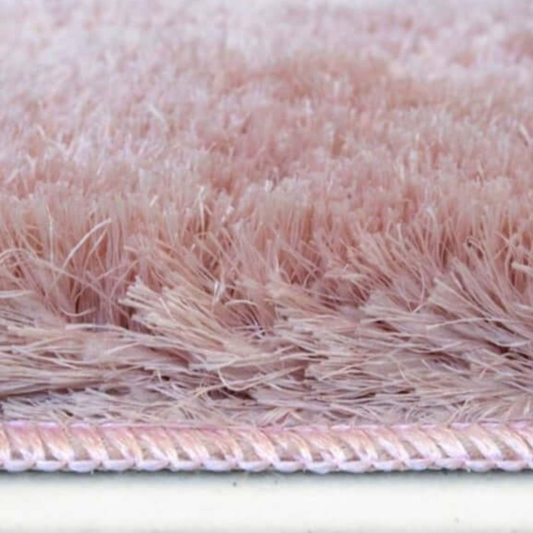 A soft washable pink shaggy rug with dense fluffy texture and neatly stitched border for cozy spaces