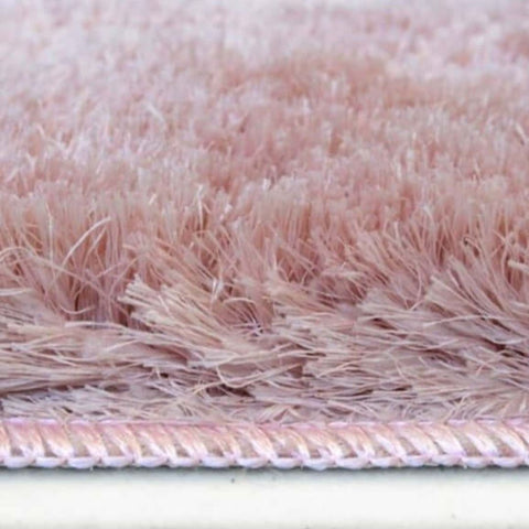 A soft washable pink shaggy rug with dense fluffy texture and neatly stitched border for cozy spaces