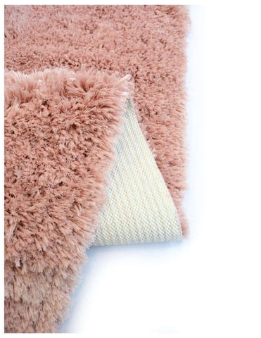 A soft washable pink shaggy rug with plush dusty rose fibers and a cream non-slip backing for bathroom use