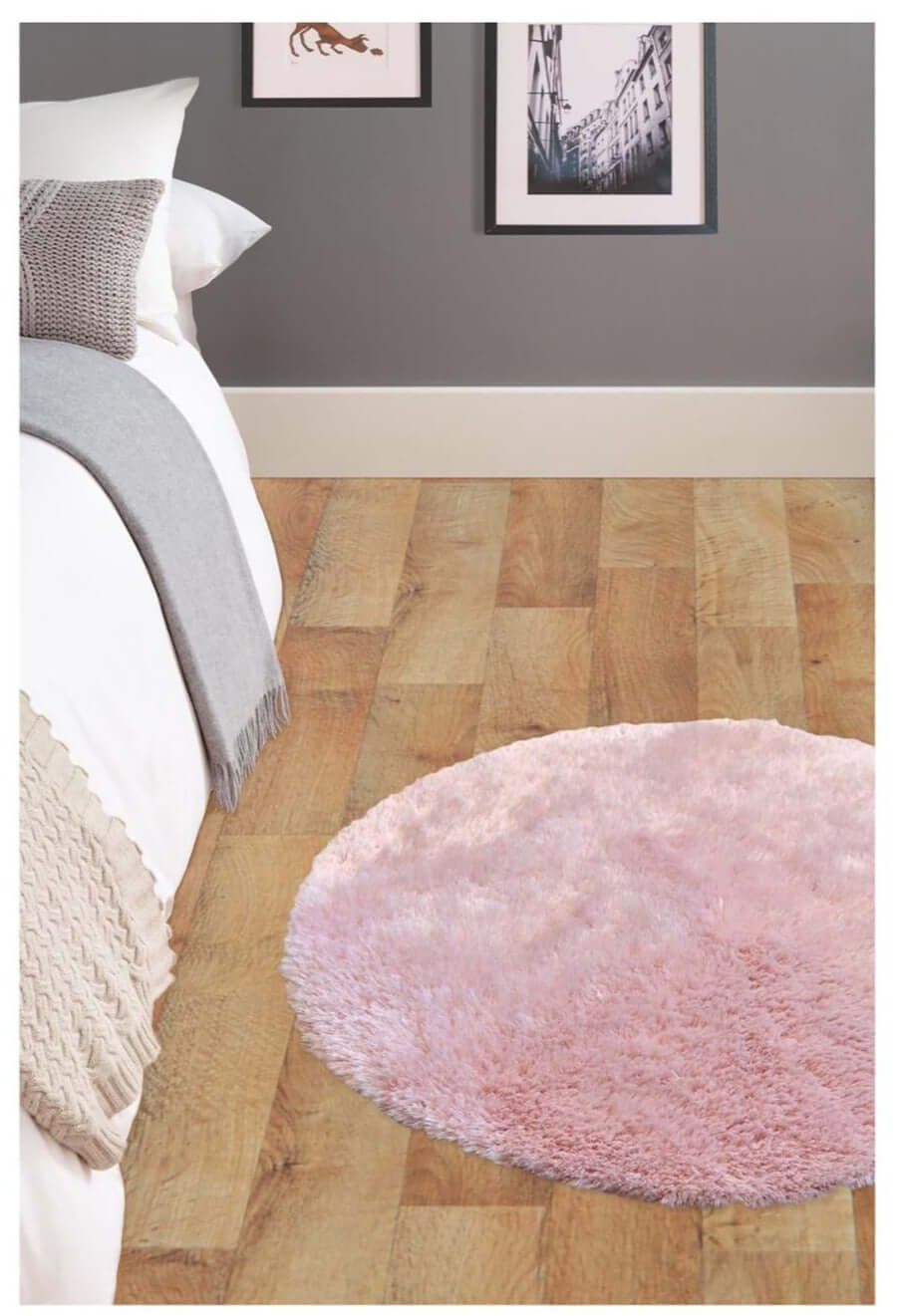 A soft washable pink shaggy rug with a plush round shape and cozy texture on a wooden floor