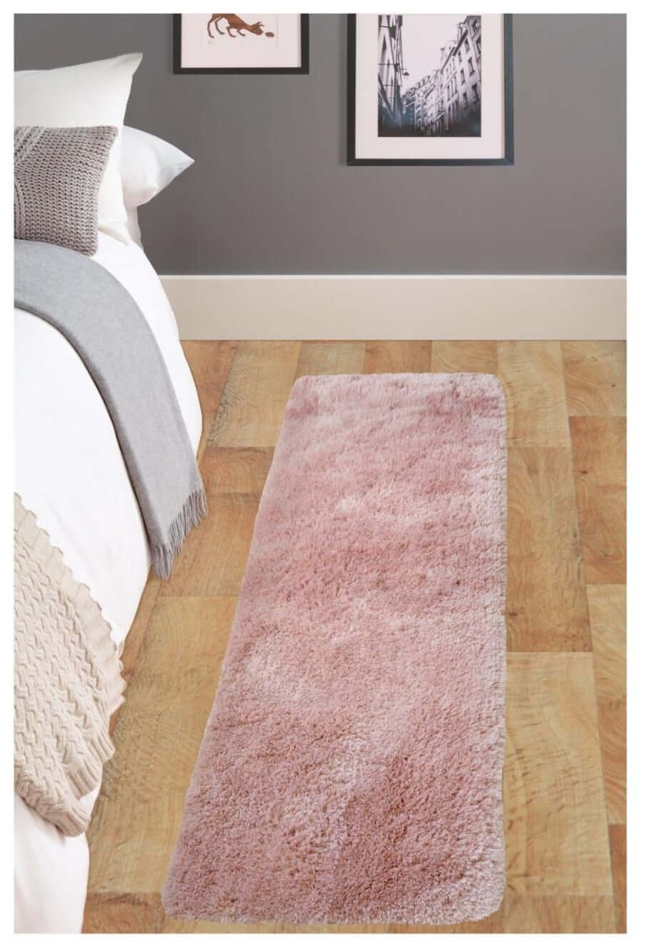 A soft washable pink shaggy rug with plush fluffy texture lies on wooden floor beside the bed