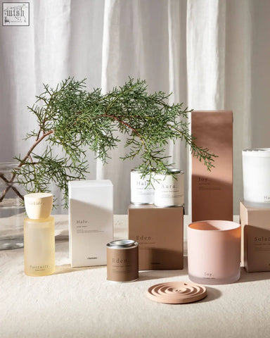 A soft pink cylindrical candle with frosted glass and minimalist branding for solace clay home spray