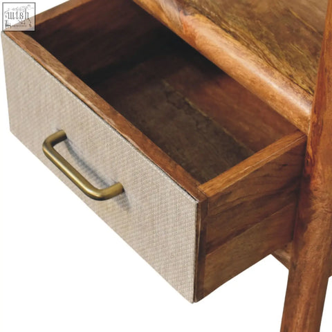 Solara rattan bedside table with beige textured fabric drawer front and brass handle set in warm wood