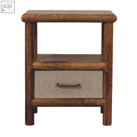 Rustic brown wooden solara rattan bedside table with a textured beige fabric drawer front and brass handle