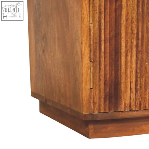 Solid wood curved bedside with warm-toned oak mango wood, vertical grooves, and brass hinges for stylish storage